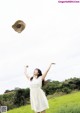 A woman in a white dress throwing a hat in the air.