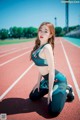 A woman sitting on a running track with her legs crossed.